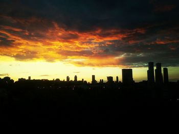 Silhouette of cityscape against cloudy sky