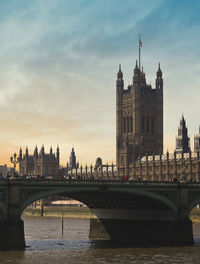 Bridge over river by buildings against sky in city