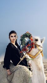 Portrait of young woman standing girl in the desert with a camel