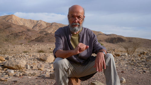 Portrait of senior man sitting on rock