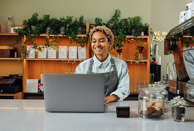 Portrait of young businesswoman using laptop while sitting on table