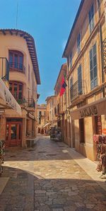 Street amidst buildings against blue sky