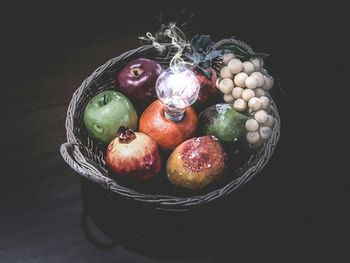 Close-up of fruits in basket on table against black background