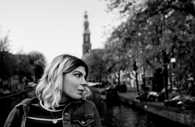 Portrait of young woman looking away against trees