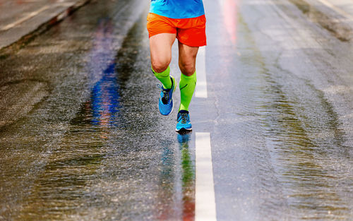 Low section of man running on wet street