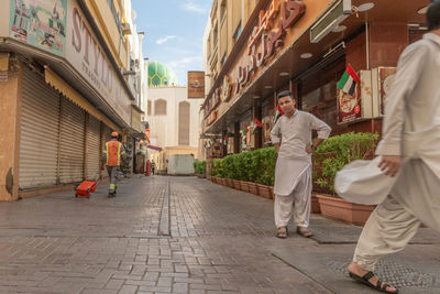 People walking on footpath amidst buildings in city