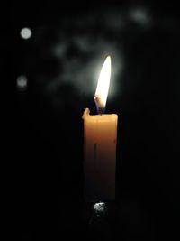 Close-up of lit candle in dark room