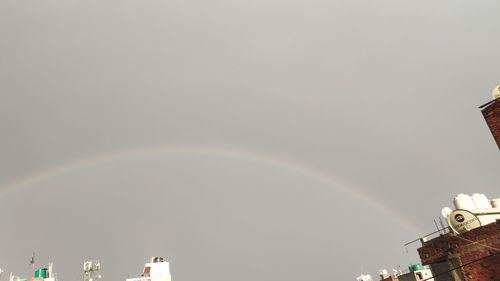 Low angle view of rainbow over building against sky