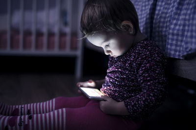 Toddler sitting on the floor playing with smartphone