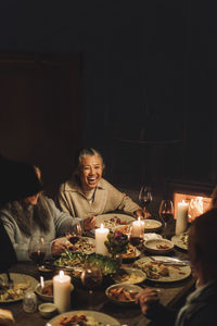 Happy senior woman with friends enjoying having food at dinner party