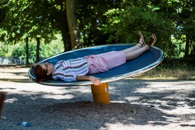 Boy lying down on land against trees