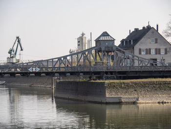 Bridge over river by buildings against sky