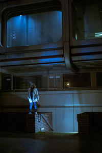 Rear view of man sitting by window at night