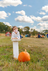 Young girl laying on bench at pumpkin farm wearing face mask	