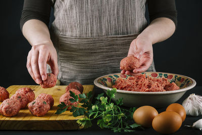 Female chef shapes minced meat to make homemade meatballs