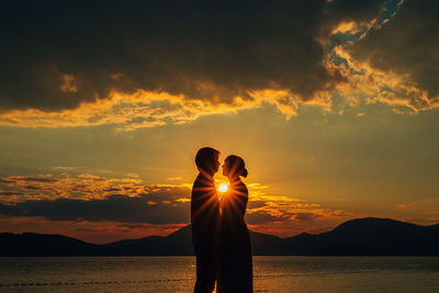 Silhouette woman standing on mountain against sky during sunset