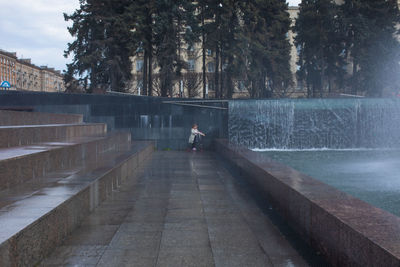 Happy little cute girl having fun in splashes a fountain