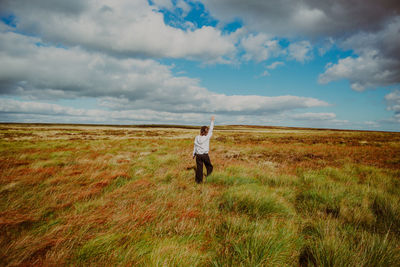 Rear view of man standing on field against sky