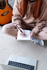 Midsection of woman writing in book at table