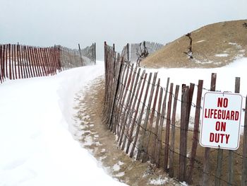 Information sign on fence against sky