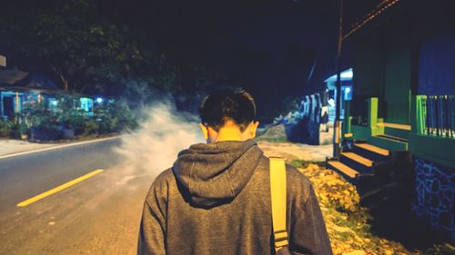 Rear view of man on illuminated street at night