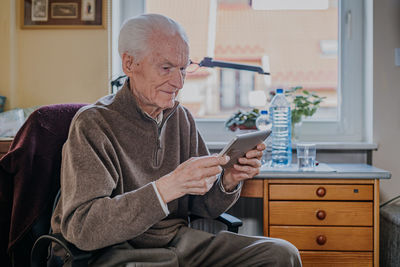 Smiling senior man using digital tablet at home