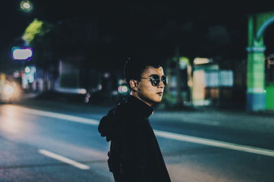 Portrait of man wearing sunglasses in city at night