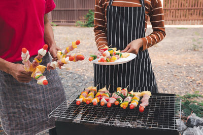 People holding food on barbecue grill