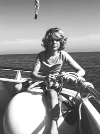 Woman sitting on boat in sea against sky
