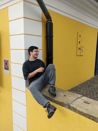 Side view of man standing against wall