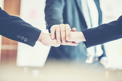 Midsection of man holding hands against white wall