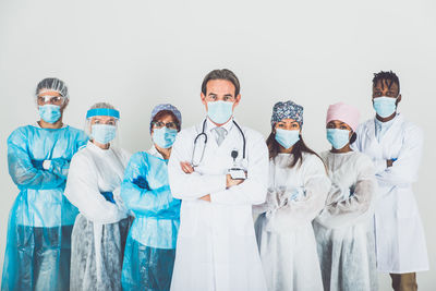 Portrait of doctors wearing mask standing against white background