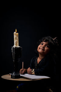 Girl holding ice cream on table against black background