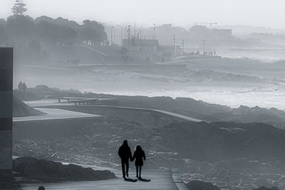 Silhouette people on snowcapped mountains against sky