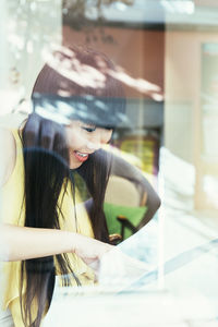 Portrait of young woman looking through glass window