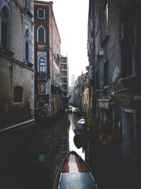 Rear view of man walking on narrow alley amidst buildings in city