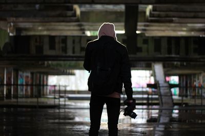 Rear view of silhouette man walking against building in city