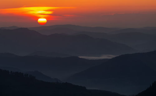 Scenic view of silhouette mountains against orange sky in rodnei mountains 