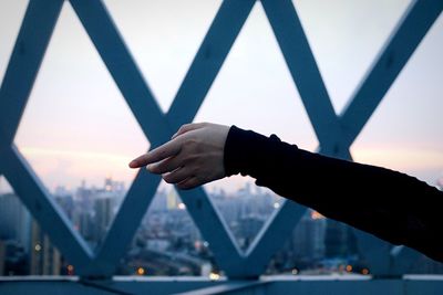 Close-up of person hand on bridge against sky