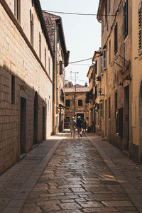 Rear view of people walking on footpath amidst buildings