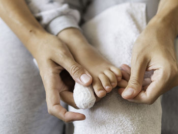 Mother bandages her child's big toe. close-up photo of kid's foot with bandaged finger. first aid