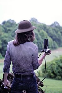 Rear view of woman photographing on field