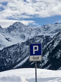 Information sign on snowcapped mountains against sky