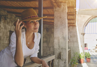 Woman wearing cowboy hat sitting on porch, jalisco mexico, portrait of happy woman using hat. 