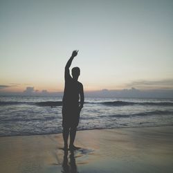 Silhouette man standing on beach against clear sky