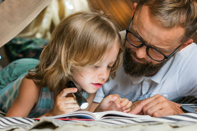 Father and son playing and reading in a kid tent at home.