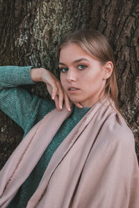 Portrait of beautiful young woman with tree trunk