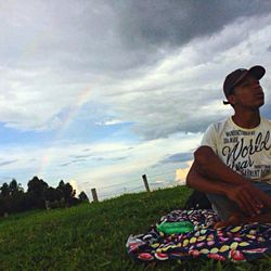 Full length of man sitting on field against sky