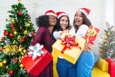 Portrait of smiling young woman standing by christmas tree