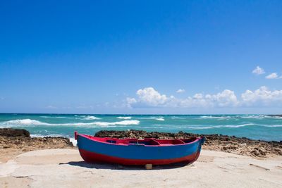 Boat moored on beach against sky